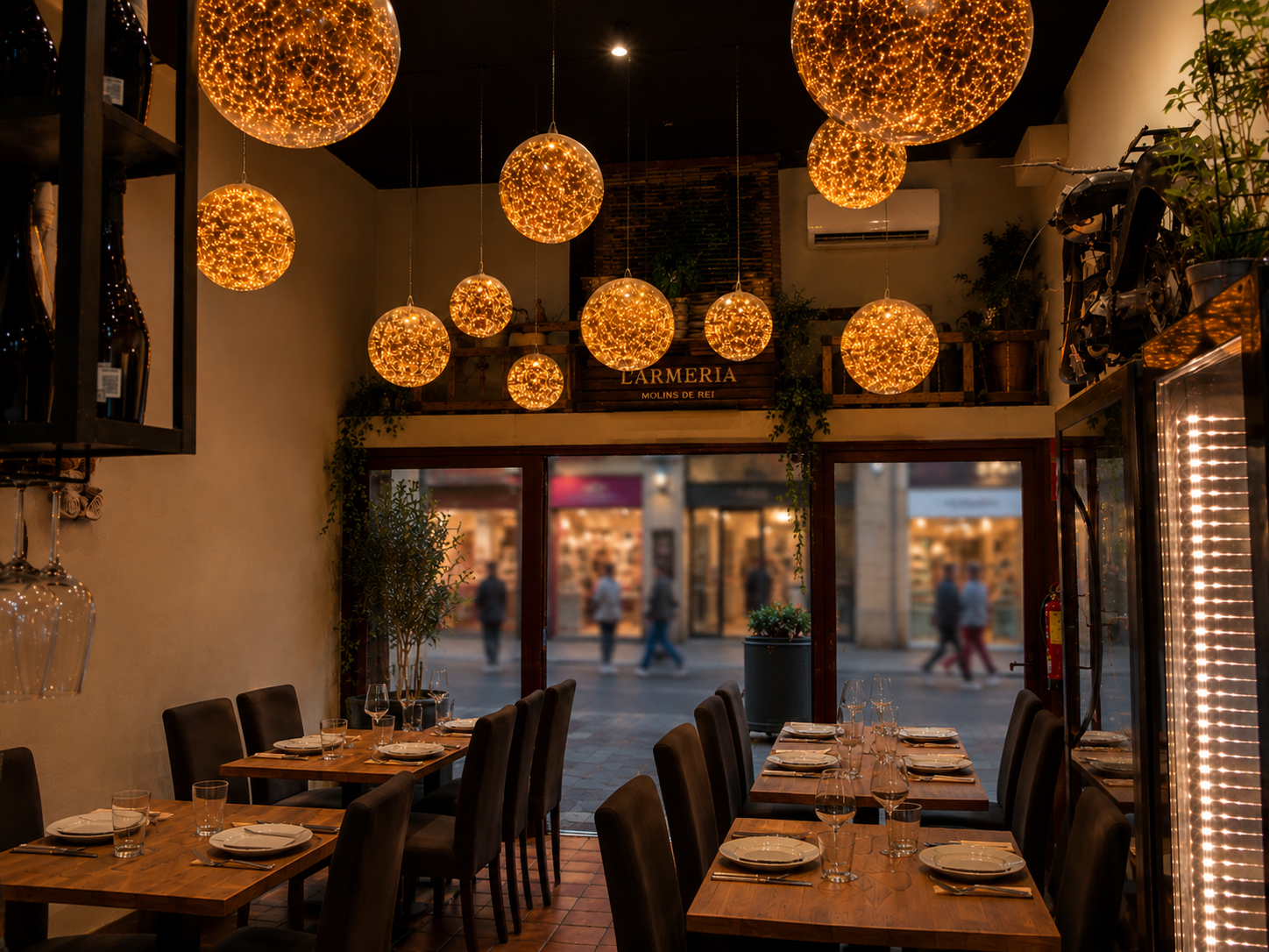Interior de L'Armeria con sus lámparas esféricas doradas y vista al Carrer Major